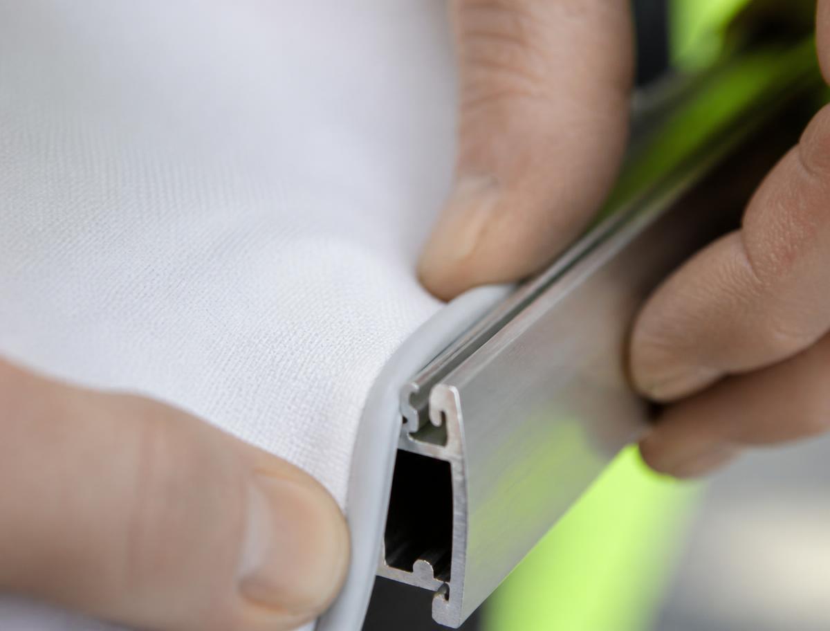 Detail of tensioned fabric being fitted into the aluminum profile